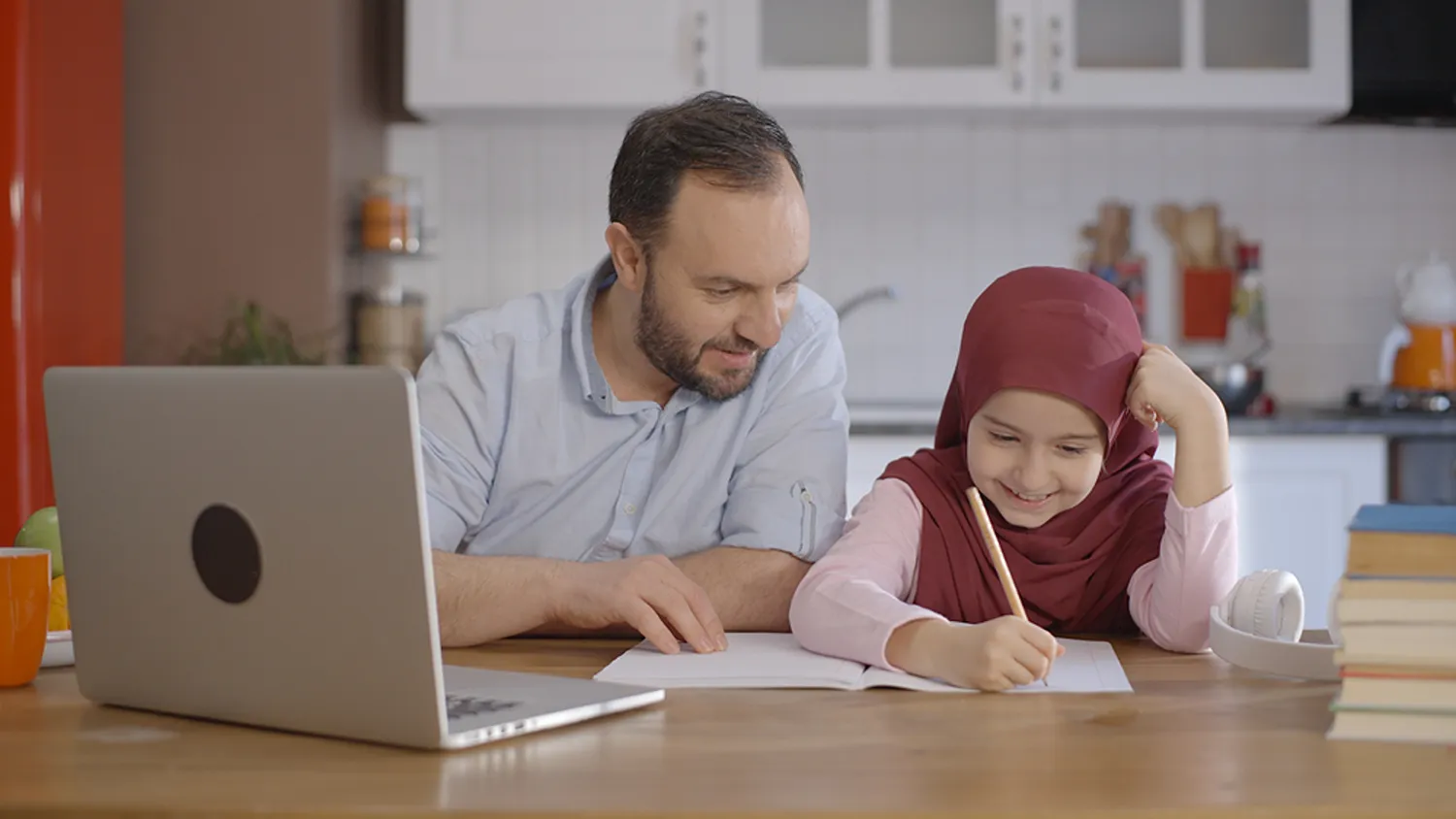 Muslim father assisting his young daughter during an online Quran learning session with Quran Janan